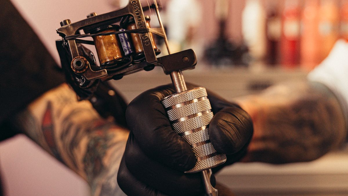 Tattoo session on arm — machine close up during ink application