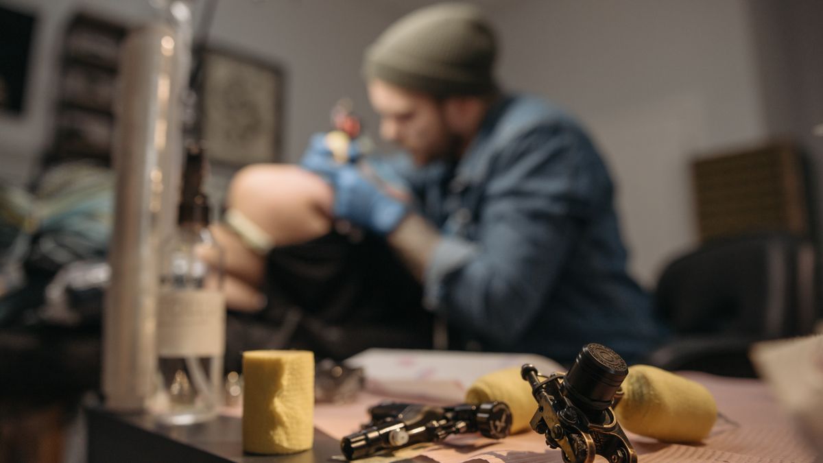 Tattoo artist applying ink to client during a session, close-up view
