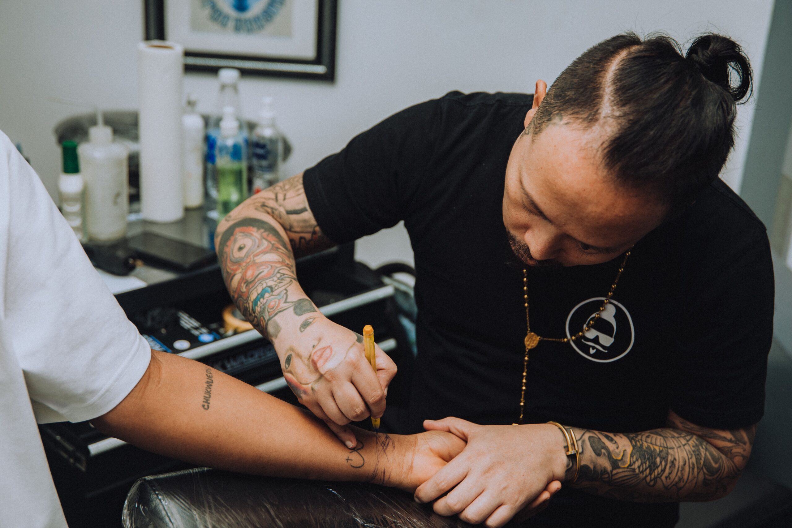 Tattoo artist drawing a design onto a client’s forearm